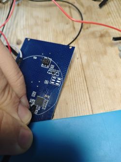 A person holding a needle touching a PCB with wiring.