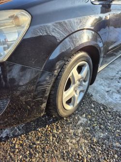 Front of a black car: headlight, front wheel, and scratches on the fender.