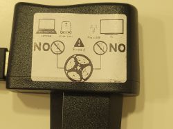 Warning sticker on a black USB device indicating prohibition of use with a computer, LAN router, and TV.