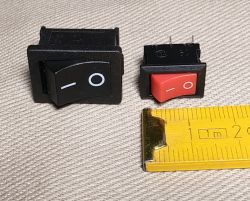 Black and red rocker switches and a yellow measuring tape on a light fabric background.
