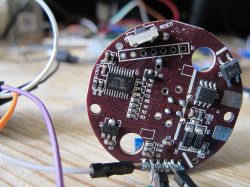 A printed circuit board with electronics and wires on a wooden table.