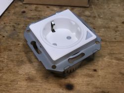 Surface-Mounted Schuko Electrical Socket SWP86-01OG White surface-mounted schuko electrical socket on a wooden surface.