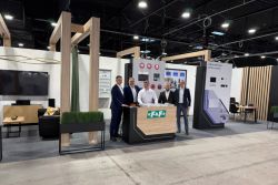 Five men at a counter with F&amp;F logo at a trade show booth inside an exhibition hall