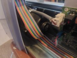 Wnętrze urządzenia mechanicznego z kolorowym kablem taśmowym podłączonym do płytki obwodu drukowanego.