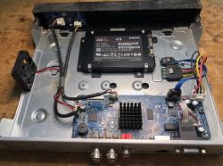 Inside of a device showing a Samsung EVO 4TB SSD connected to mainboard inside metal case.