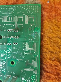 Zdjęcie tylnej strony płytki drukowanej z widocznymi śladami zaśniedzenia i zielonego nalotu.