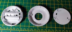 Disassembled PIR motion sensor casing on a green mat with a scale.