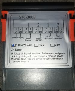 Zbliżenie na termostat STC-3008 z widocznymi oznaczeniami złączy i napięć