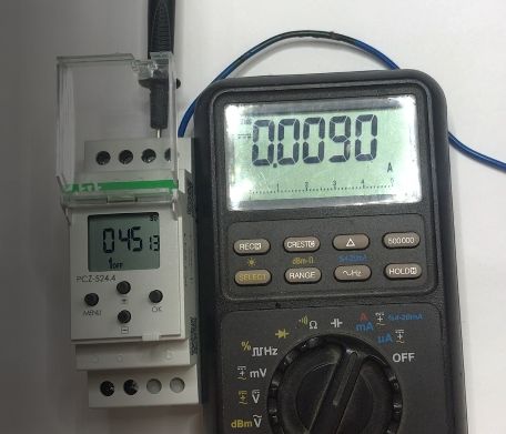Elektroniczny miernik i cyfrowy przekaźnik czasowy na białym tle, z wyświetlonymi odczytami.