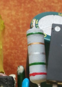 Zbliżenie na rezystor osiowy z kolorowymi paskami na płytce drukowanej