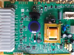 Zdjęcie płytki drukowanej z różnymi elementami elektronicznymi, w tym radiatorem i kondensatorami.