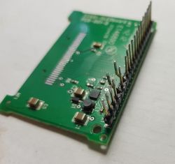 Close-up of a green circuit board with soldered pins.