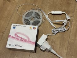 Wi-Fi LED light strip kit with remote, power supply, and box on wooden floor