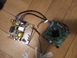 Dwie płytki elektroniczne połączone przewodami leżące na drewnianej podłodze.