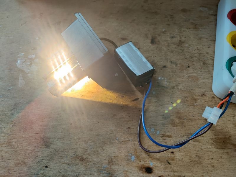 Wall Lamp with Open Casing Wall lamp with open casing, connected by cable, emitting bright light.