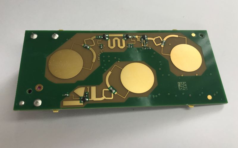 Green PCB with three large gold circular pads and gold traces, top view