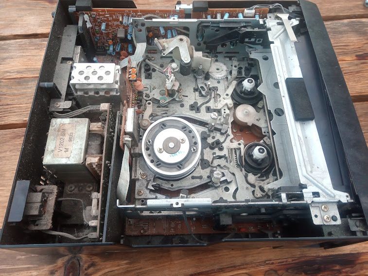 Wnętrze rozebranego magnetowidu Akai z widoczną mechaniką i elektroniką