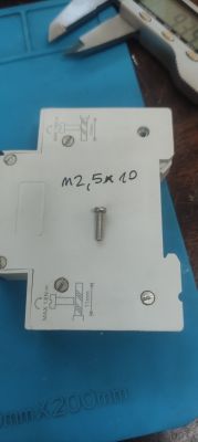 A screw M2.5x10 resting on a white component with marked specifications.