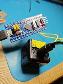 STM32 microcontroller with wiring connected to a black power module on a desk