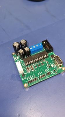 Soldered controller board with Atmel ATMEGA328P microcontroller Soldered PCB with capacitors, microcontroller and connectors on a blue surface