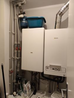 Gazowy piec Beretta wiszący na ścianie w pomieszczeniu gospodarczym z podłączoną instalacją.