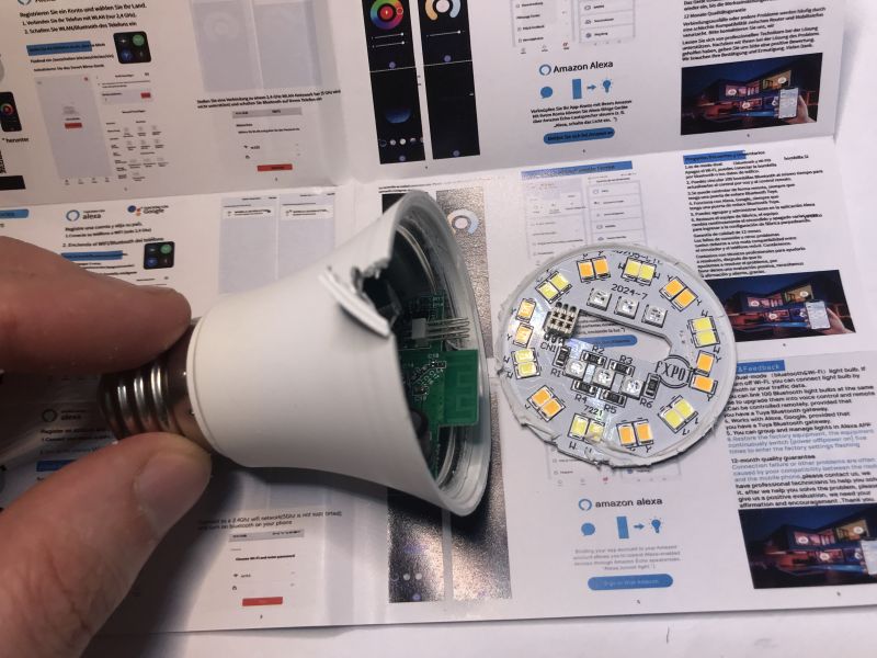 Interior of TNCE Smart E27 LED Bulb with User Manual in Background View of the interior of a TNCE Smart E27 LED bulb with the dome and LED board removed, against a background of the user manual.