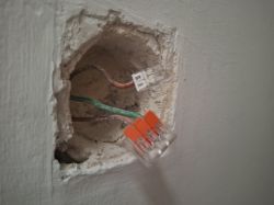 Zbliżenie na puszkę elektryczną ze złączami Wago i przewodami.