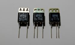 Three Bridge Rectifiers on Gray Surface Three bridge rectifiers with unreadable labels on a gray surface.