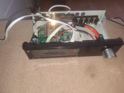 Open audio device case showing circuit boards, wiring, front display, and a large control knob