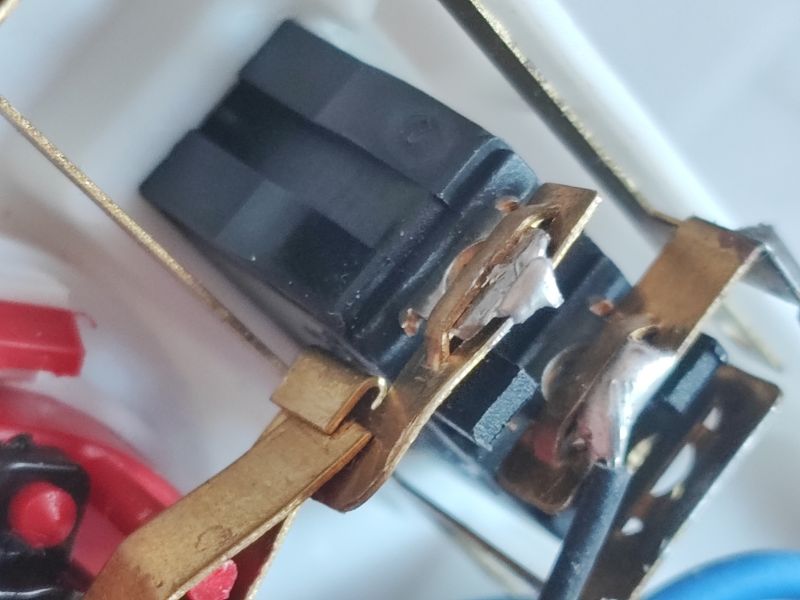 Zbliżenie uszkodzonej wewnętrznej części listwy zasilającej z widocznym zimnym lutem.