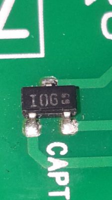 Zbliżenie na czarny element SMD z napisem „IOG 5” na zielonej płytce PCB przy oznaczeniu „CAPT”.