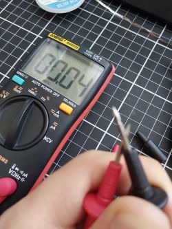 ANENG AN8009 Multimeter – Resistance Measurement Test ANENG AN8009 multimeter with display showing 0.004 ohms, with probes in hand.