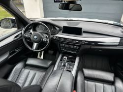 Interior of a BMW car featuring a steering wheel, dashboard, and leather seats.