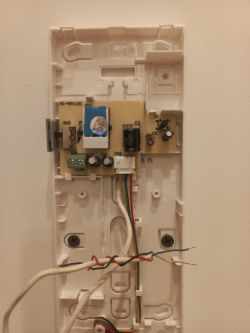 Wnętrze mechanizmu domofonu z widocznymi czterema przewodami: białym, niebieskim, czerwonym i czarnym.