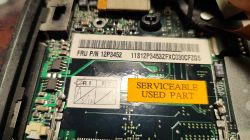 Zbliżenie na płytę główną z etykietami FRU i naklejką „SERVICEABLE USED PART”