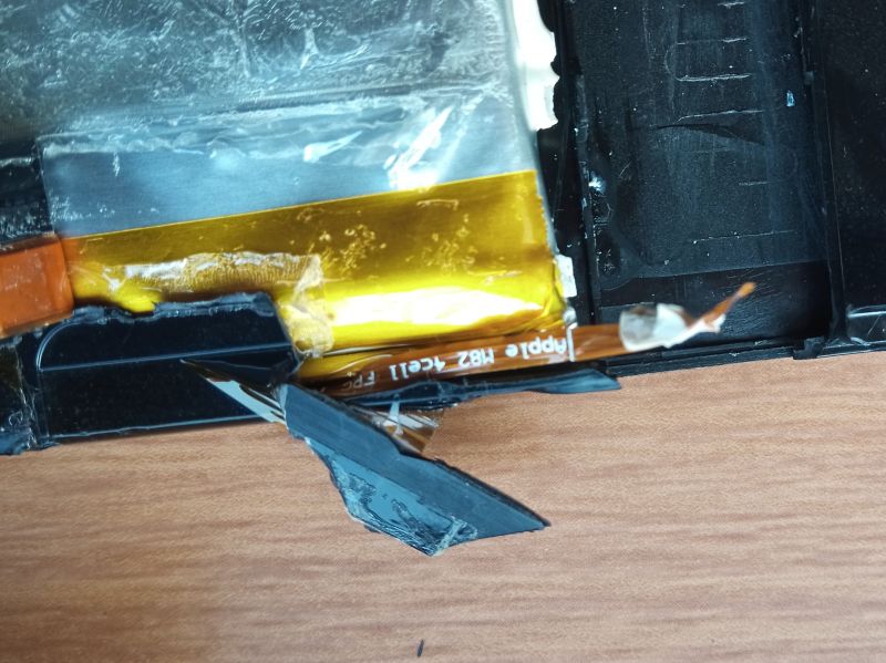 Zbliżenie na uszkodzoną baterię MacBooka Air z odkrytą taśmą flex PCB