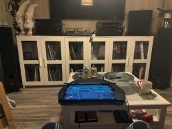 Stolik z laptopem, filiżanką, okularami i zestawem stereo w tle