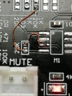 Zbliżenie na płytkę drukowaną z przewodem przylutowanym do punktu oznaczonego jako MUTE.