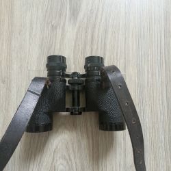 Czarne lornetka HEDLER 8x30 z szerokim skórzanym paskiem, bez gumowych nakładek na okulary, leży na jasnym drewnianym podłożu.