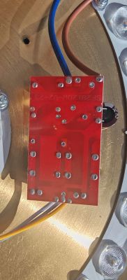 Czerwona płytka PCB sterownika LED z lutami i przewodami na drewnianym podłożu