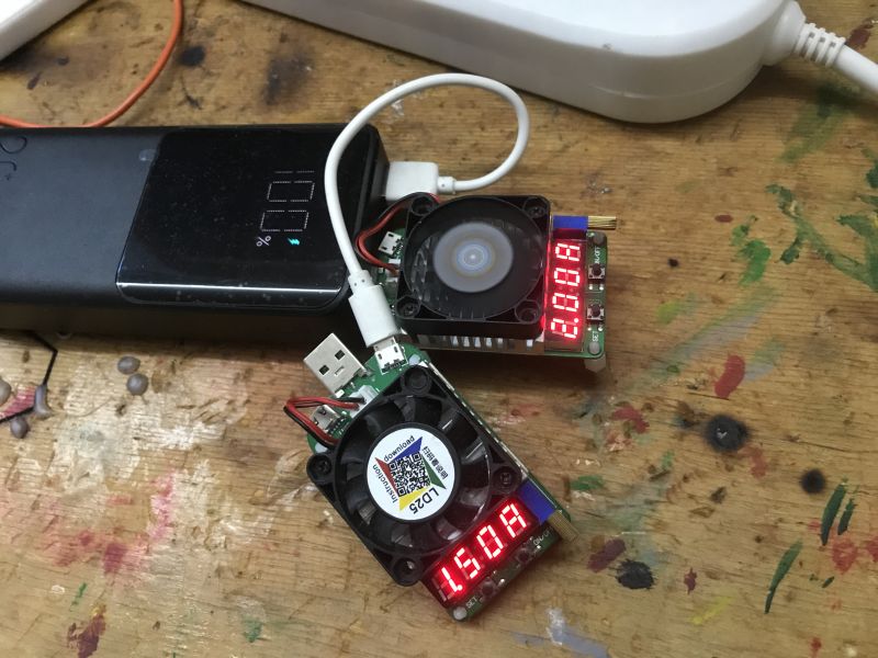Powerbank z podłączonymi testerami elektronicznymi na drewnianym stole.