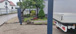 Widok bramy wjazdowej z przekrzywionym słupkiem i niedokończoną posesją