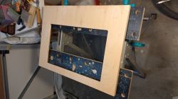 Wooden frame for a monitor cover mounted on a workbench.