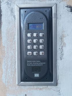 Panel domofonu z klawiaturą numeryczną i instrukcjami.