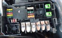 Car fuse box with visible colorful fuses.