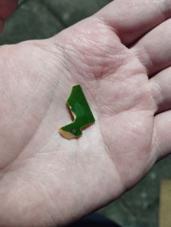 Uszkodzony fragment płytki drukowanej trzymany na dłoni.