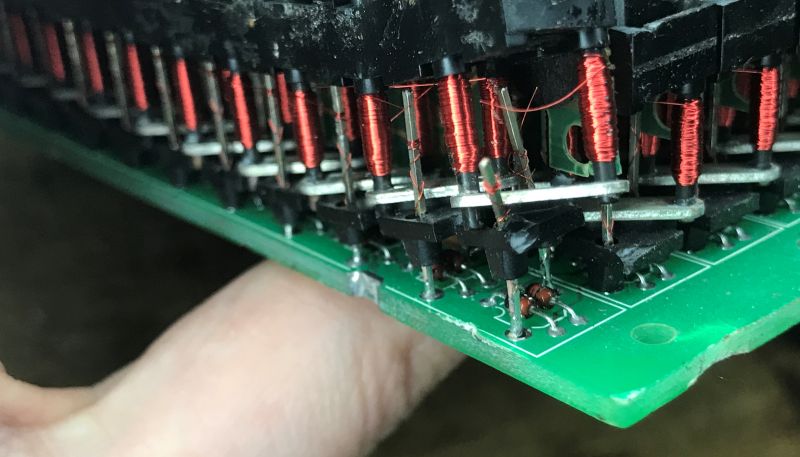 Close-up of red electromagnet coils and diodes on a green PCB