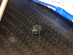 Gumowy element przycisku leżący na ciemnej powierzchni.