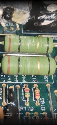 Zbliżenie na elementy elektroniczne na płytce drukowanej, w tym dwa zielone rezystory.