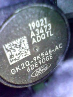 Zbliżenie na wtryskiwacz z widocznymi oznaczeniami i kodem QR.